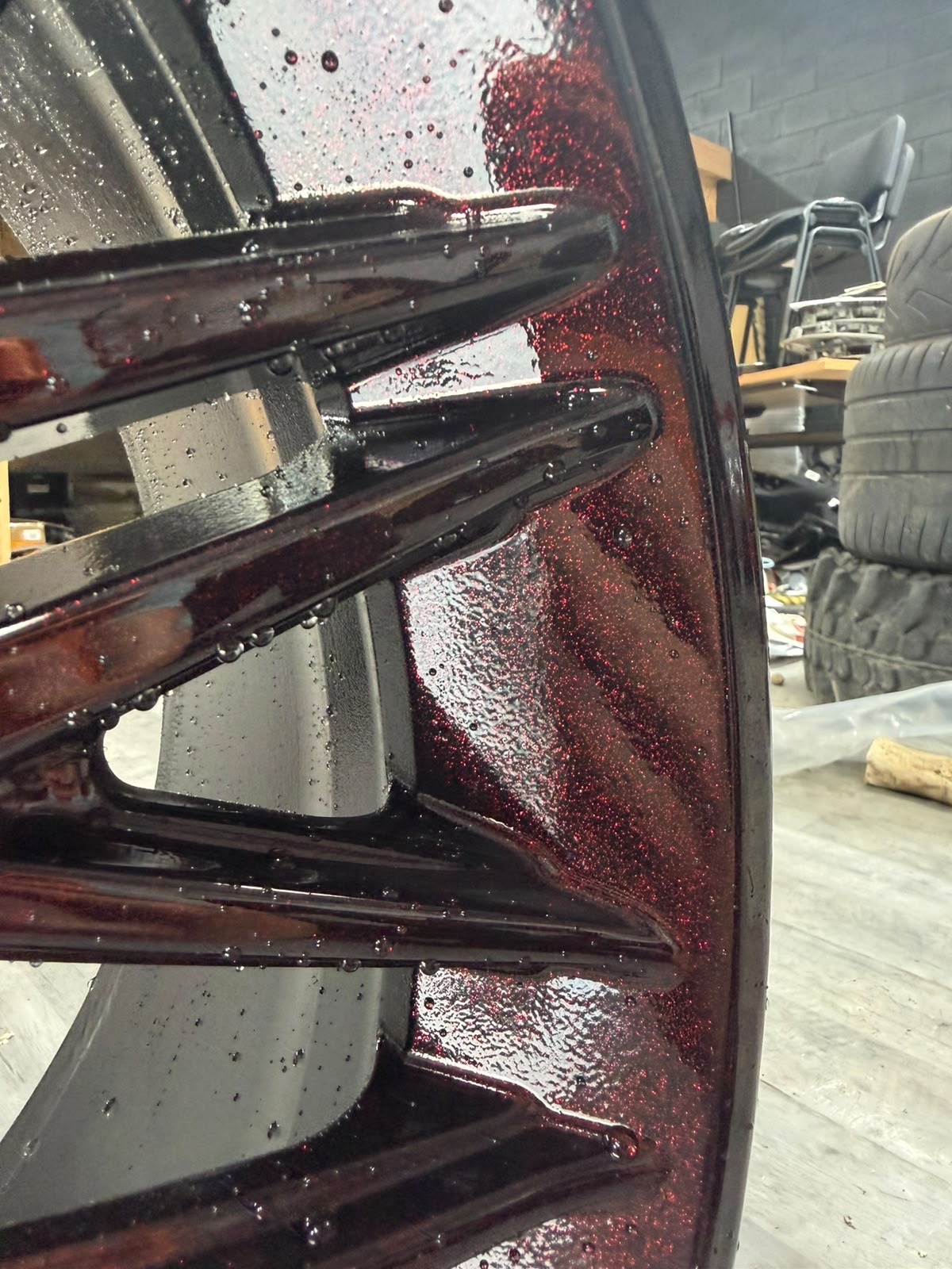 Close-up of candy red metallic flake finish on a refurbished alloy wheel