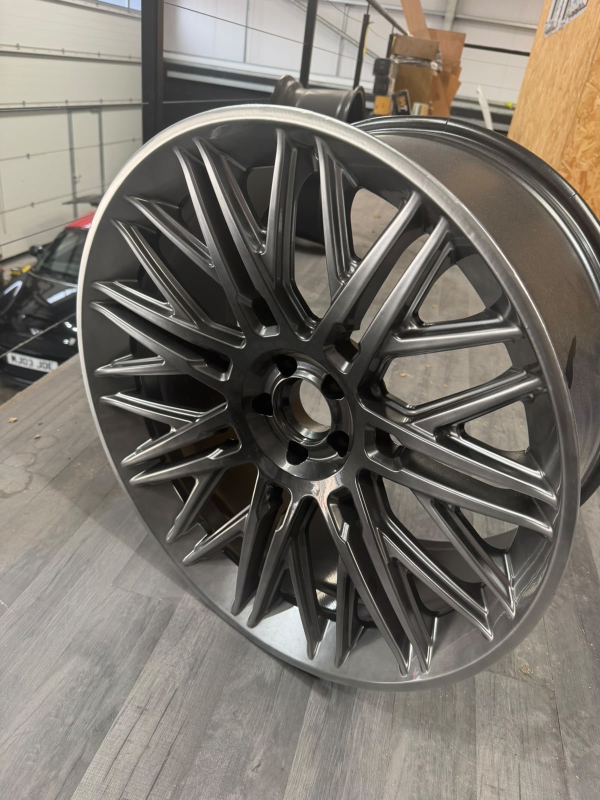 Freshly refurbished multi-spoke alloy wheel in gunmetal grey in the workshop