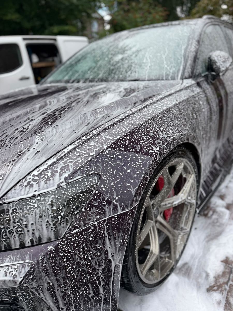 Snow foam dwelling on the Audi RS6 front wing with water beading on the paint