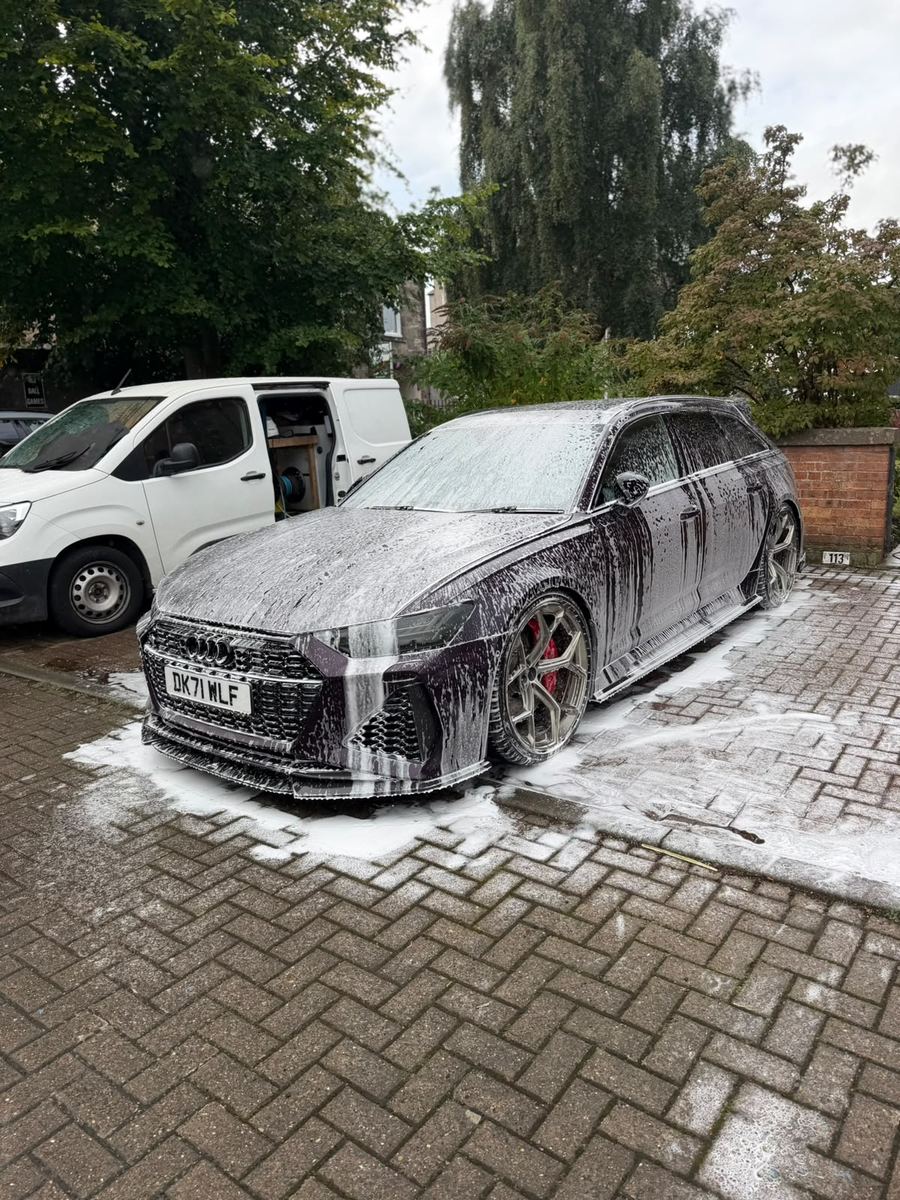 Audi RS6 under a full blanket of snow foam on the driveway