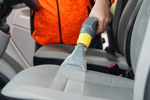 Car seat being shampooed and wet-vacuum extracted during a deep clean