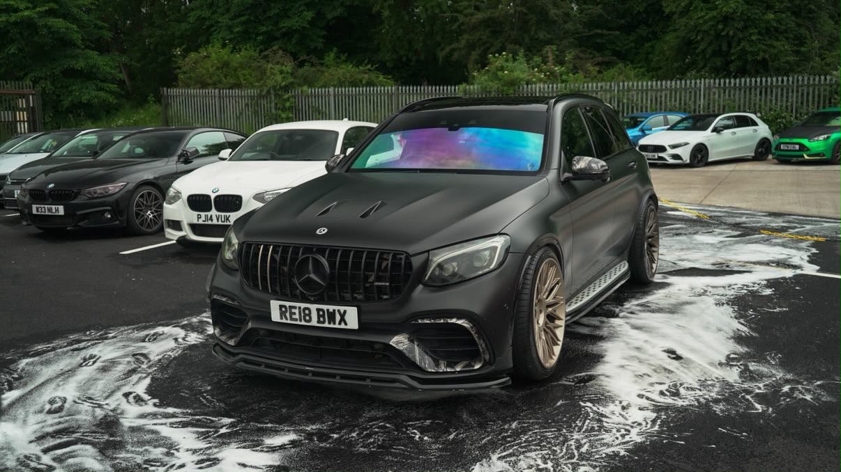 Matte black Mercedes-AMG GLC 63 on bronze wheels during a snow-foam safe wash
