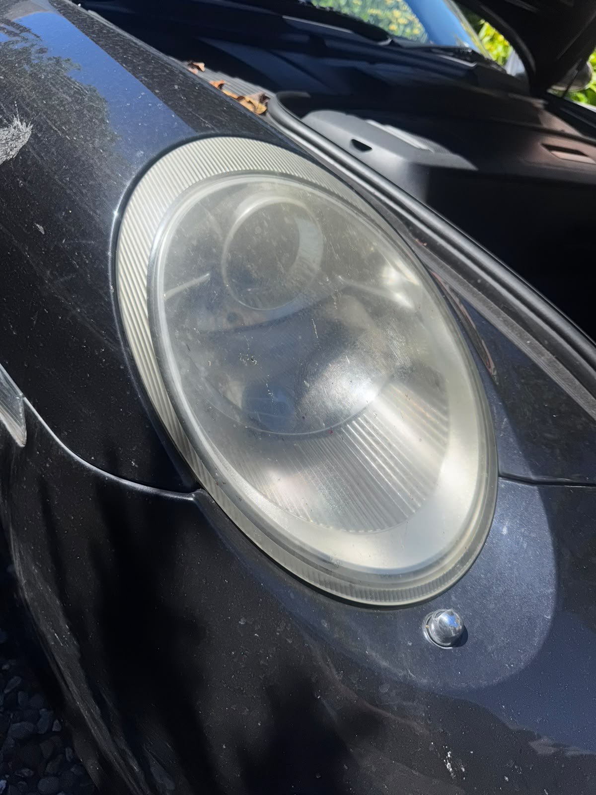Heavily oxidised, hazy Porsche 911 headlight before restoration
