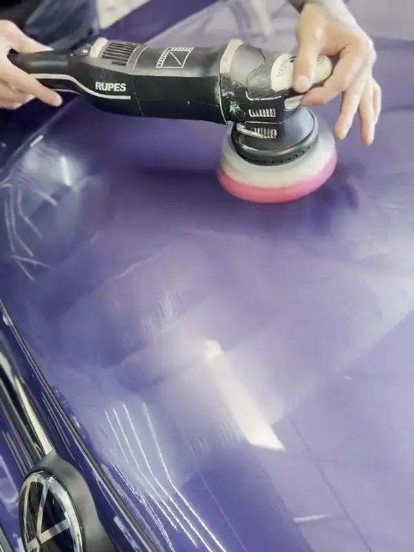 Machine polishing a purple car during a gloss enhancement